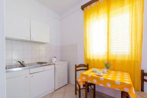 a small kitchen with a table and a yellow curtain at Apartments Diana in Dubrovnik