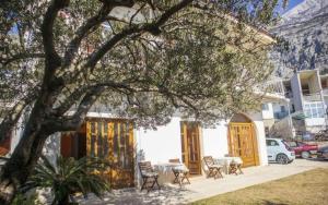 ein Haus mit einem Tisch, Stühlen und einem Baum in der Unterkunft Apartments Sunny in Makarska