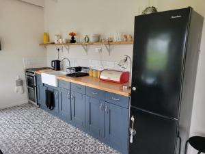 una cucina con armadi blu e frigorifero nero di The Tin Shed a Tara