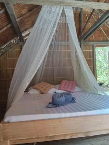 a bed in a room with a mosquito net at Pin Wawiyai Natural Homestay in Yennanas Besir