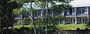 Shady CoveにあるEdgewater Inn Shady Coveの青いバルコニーと木々が備わる白い大きな建物