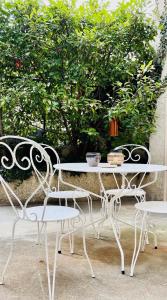 ein weißer Tisch und Stühle neben einem Busch in der Unterkunft Villa Lucie, 4 à 8 personnes in Clermont-Ferrand
