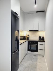 a kitchen with white cabinets and a refrigerator at Apartament Diamond in Częstochowa