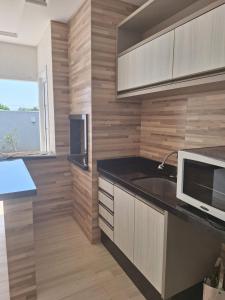 a kitchen with a sink and a microwave at Casa Bourbon in Foz do Iguaçu