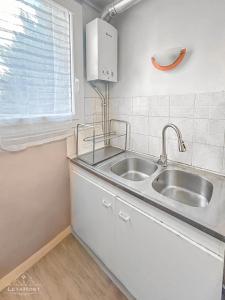 eine weiße Küche mit Spüle und Fenster in der Unterkunft Appartement moderne avec Wi-Fi et Balcon in Choisy-le-Roi