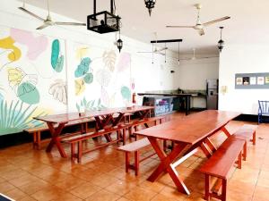a dining room with wooden tables and a kitchen at Poco a Poco Hostel in León