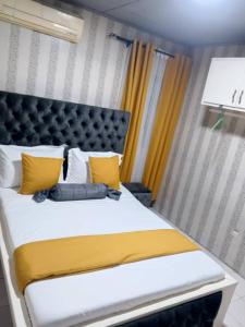 Un dormitorio con una cama grande con almohadas amarillas y blancas. en Bonamoussadi Gardens - Piscine-Wifi- Eau- Electricite 24h sur 24, en Douala