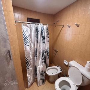 Un baño con inodoro y cortina de ducha en Amplia casa a solo unos metros del centro - RentVGB, en Villa General Belgrano