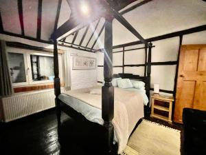 ein Schlafzimmer mit einem Himmelbett in einem Zimmer in der Unterkunft Beautiful 17th Century Cottage in Buckinghamshire