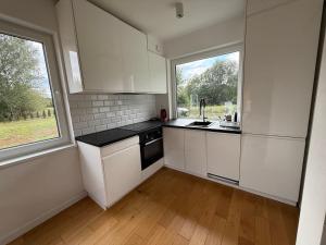a kitchen with white cabinets and a large window at Dom przy lesie in Lipiany