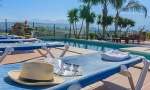 Un grupo de mesas con sombreros y vasos junto a una piscina. en Villa Quilin, en Alhaurín el Grande
