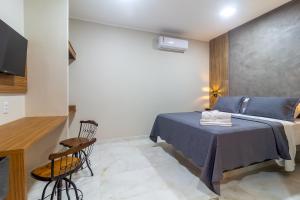 a bedroom with a bed and a table in a room at Cavalo Marinho Flats in Arraial d'Ajuda