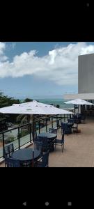 a patio with tables and white umbrellas on the beach at Maraca Beach Residence 2 in Porto De Galinhas