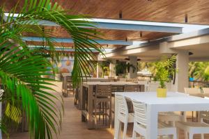 AssiniePalms Resort Assinie Managed by Accor的一间设有白色桌椅的餐厅,种植了植物