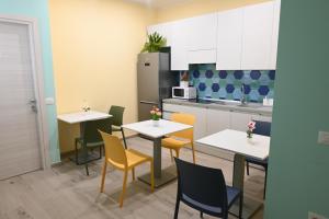 a kitchen with two tables and chairs and a refrigerator at Pane Amore e B&B in Pompei