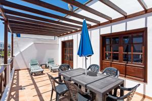 patio ze stołem, krzesłami i niebieskim parasolem w obiekcie Apartment Limonade Deluxe Main Center Playa Blanca By PVL w mieście Playa Blanca