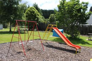 a playground with two swings and a slide at Fairy Springs Motel in Rotorua
