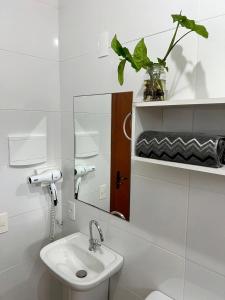 a white bathroom with a sink and a mirror at Encanto Acomodações in Guarda do Embaú
