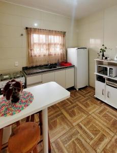 a kitchen with a white table and a white refrigerator at Encanto Acomodações in Guarda do Embaú
