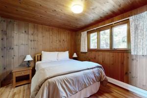 ein Schlafzimmer mit einem Bett in einer Holzhütte in der Unterkunft Reed Shore Cottage in Bass Harbor