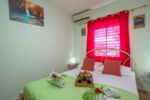 a bedroom with two beds with a red window at Villa Cocotier in Sainte-Anne