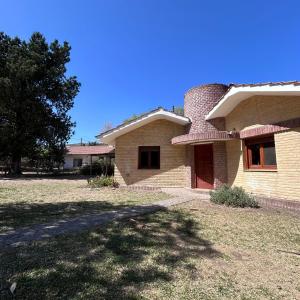 una casa de ladrillo con un árbol delante de ella en Amplia casa a solo unos metros del centro - RentVGB, en Villa General Belgrano