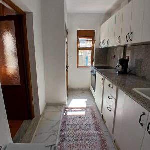 a kitchen with white cabinets and a rug on the floor at Betty's Home in Korçë