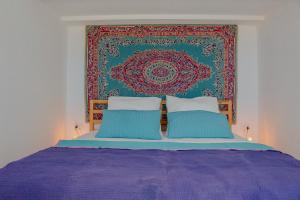 un lit avec deux oreillers bleus devant une tapisserie dans l'établissement Il Polpo Nero l Villa Vue Mer, Piscine, Rooftop & 2 Vespa, à Porto Columbu - Perdʼe Sali 52 autres photos