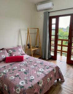 a bedroom with a bed with a pink comforter at Encanto Acomodações in Guarda do Embaú +47 photos