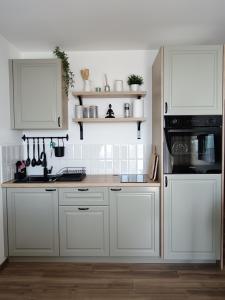 科帕奥尼克Apartman TRAMONTO Kopaonik的白色的厨房配有白色橱柜和炉灶。