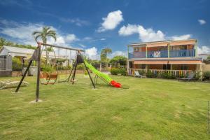 a playground with a slide in a yard with a house at Villa Cocotier in Sainte-Anne