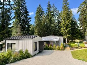 a white shed with a black roof in a garden at Villa Vlada vacation houses in Saulkrasti