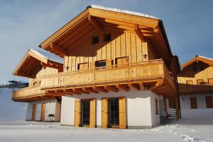 a large wooden building with a balcony in the snow at Almhäuser Filzsteinalpe Almhaus 205 in Krimml