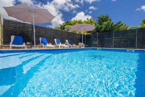 a swimming pool with chairs and umbrellas on the side at Villa Cocotier in Sainte-Anne +24 photos