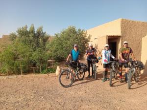 a group of people standing with bikes in front of a building at Tazoult Ouzina in Ouzina