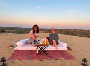 斋沙默尔Hotel Hostel Stay Jaisalmer的两个女人坐在海滩上的毯子上 更多17张照片