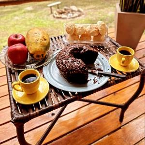 a table with a tray of donuts and cups of coffee at Chalé beija flor in Paraisópolis +116 photos