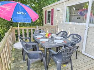 a table with chairs and an umbrella on a deck at Mobile Home Eden in Litteau +10 photos