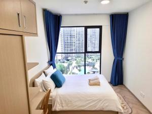 a bedroom with a bed with blue curtains and a window at EcoVinhomes Grand Park in Long Bình +126 photos
