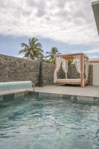 a pool with a gazebo and a bed at La villa Grand Bois avec sa piscine chauffée in Saint-Pierre