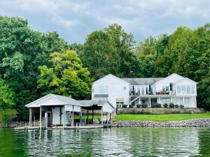 a large white house with a dock on the water at 6 BD Smith Mountain Lakefront Escape sunset in Moneta