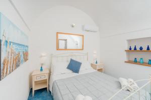 a white bedroom with a bed and a mirror at Albergo Diffuso Bacco Furore in Furore