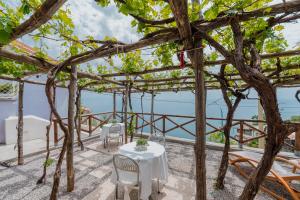 a table and chairs on a patio with the ocean in the background at Albergo Diffuso Bacco Furore in Furore
