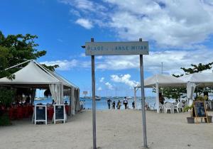 a sign for a beach with tables and chairs at Sublime appartement pour 4pers - Clim - Vue mer - Parking in Les Trois-Îlets