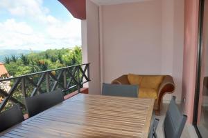 a balcony with a wooden table and a chair at Sublime appartement pour 4pers - Clim - Vue mer - Parking in Les Trois-Îlets