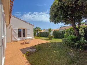 a patio with a table and a tree in a yard at La Garenne in Saint-Jean-de-Monts