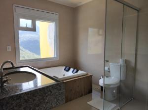 a bathroom with a tub and a toilet and a window at Hotel Du Rastro in Lauro Müller +45 photos
