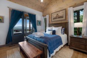 ein Schlafzimmer mit einem Bett mit einer blauen Bettdecke in der Unterkunft Elevated Escape - Luxurious Mountain Views - Hot Tub, Game Room, Fire Pit, Full Mountain Views - Escape to Luxury North Georgia in Cherry Log