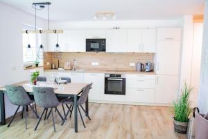a kitchen with white cabinets and a wooden table and chairs at Ferienwohnung Passhöhe - Familienurlaub- Wanderurlaub Schwarzwald - Hunde willkommen- Hochschwarzwaldcard - Haus Wiesenquelle in Feldberg