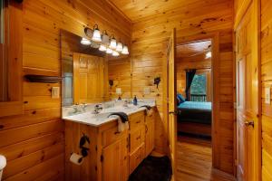 a log cabin bathroom with a sink and a mirror at Escape to Dream Catcher - Enjoy cozy accommodations, and a variety of entertainment options including a hot tub, game room, and in Blue Ridge +50 photos